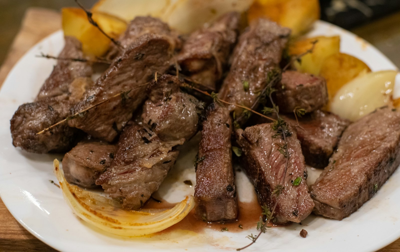 Seared steak bites with herbs and roasted potatoes on a plate