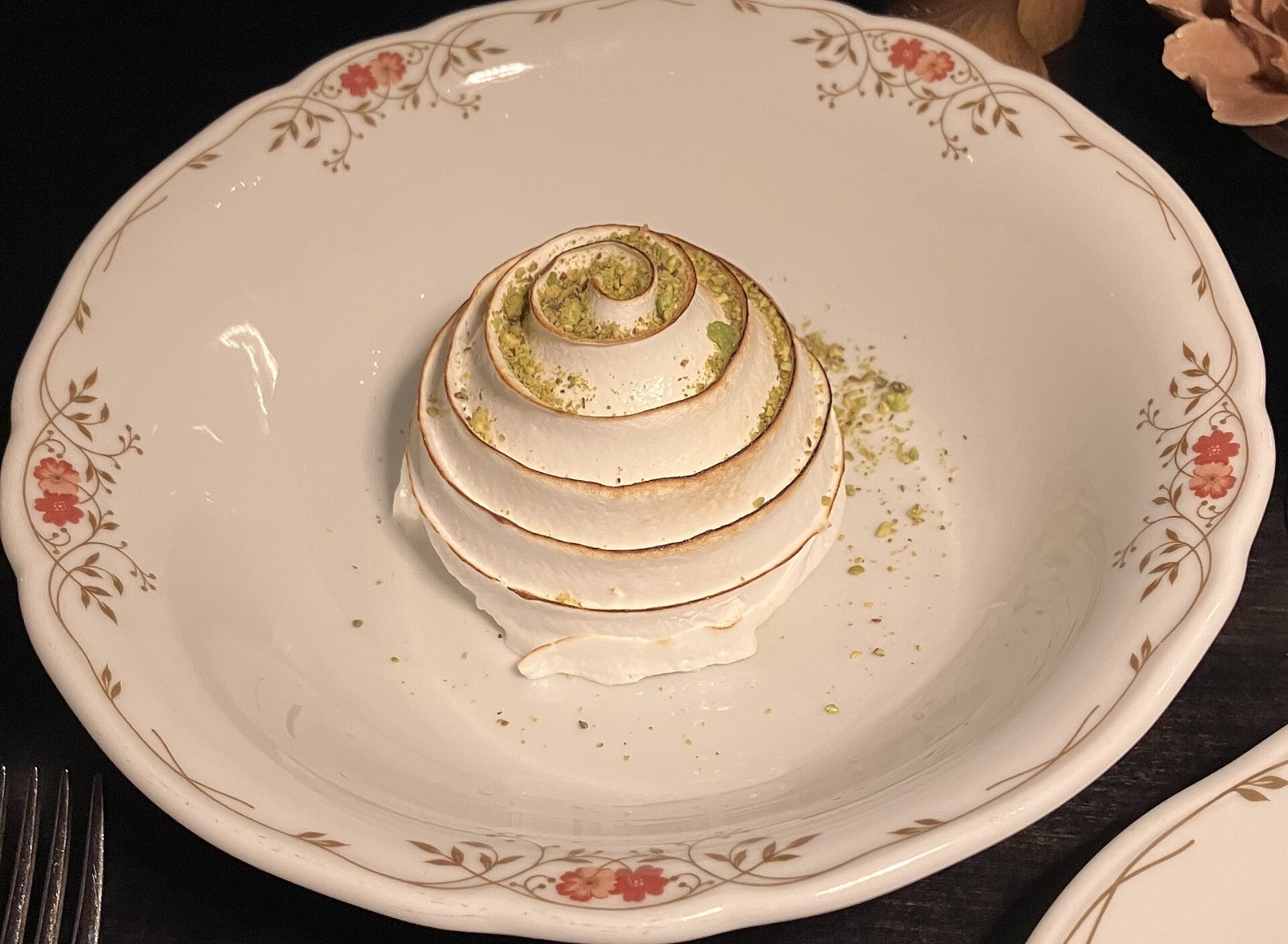 Baked Alaska with a golden meringue dome on a vintage china plate