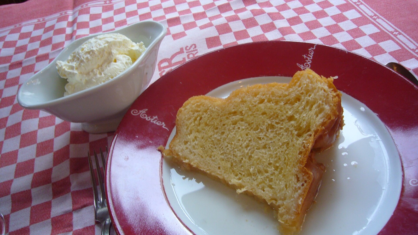 Slice of golden buttered rum cake on a plate with whipped cream