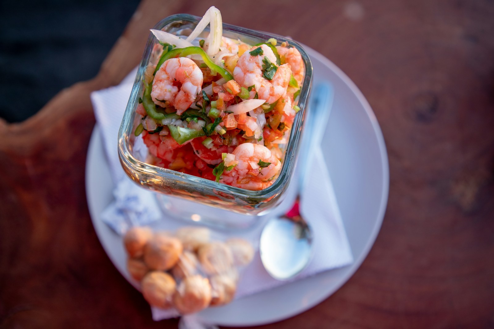 Chilled shrimp cocktail in a glass dish with tomato and fresh herbs