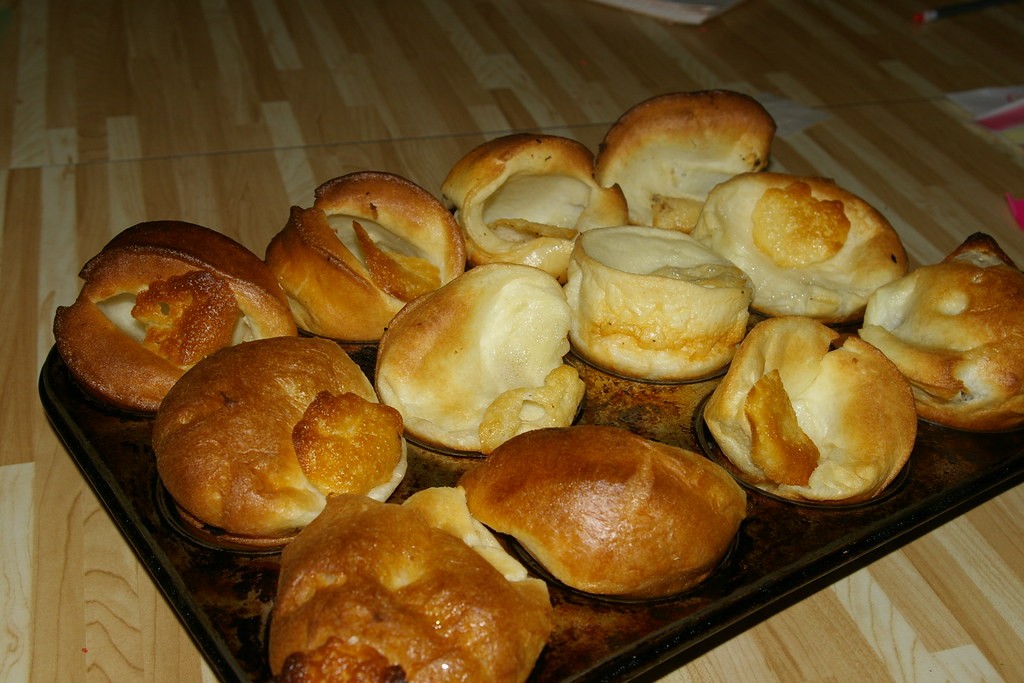 Tall puffed golden Yorkshire puddings in a muffin tin