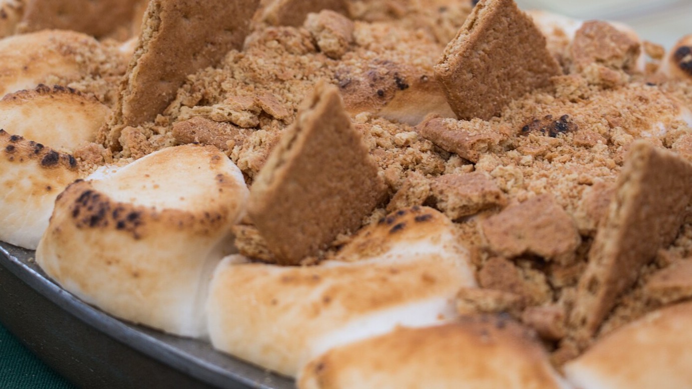 Baked dip with golden marshmallows and graham cracker pieces in a pan