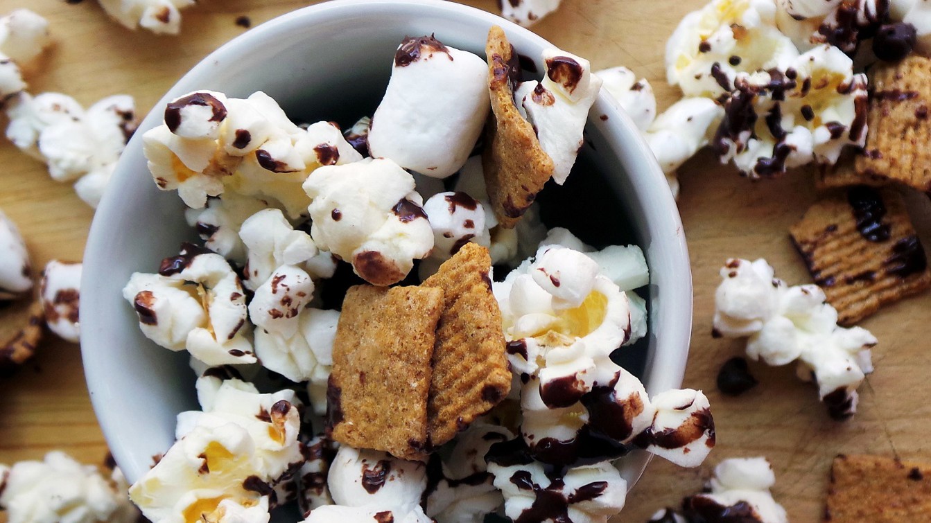 Popcorn with marshmallows, graham cereal and chocolate drizzle in a bowl