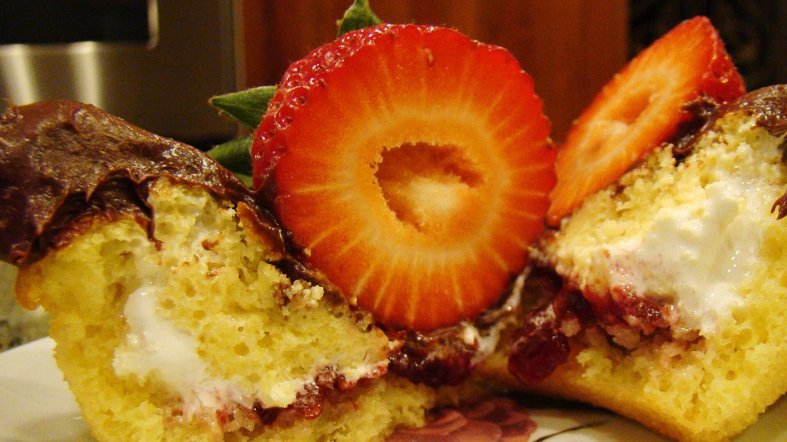 Cupcakes filled with marshmallow and topped with chocolate and fresh strawberry slices