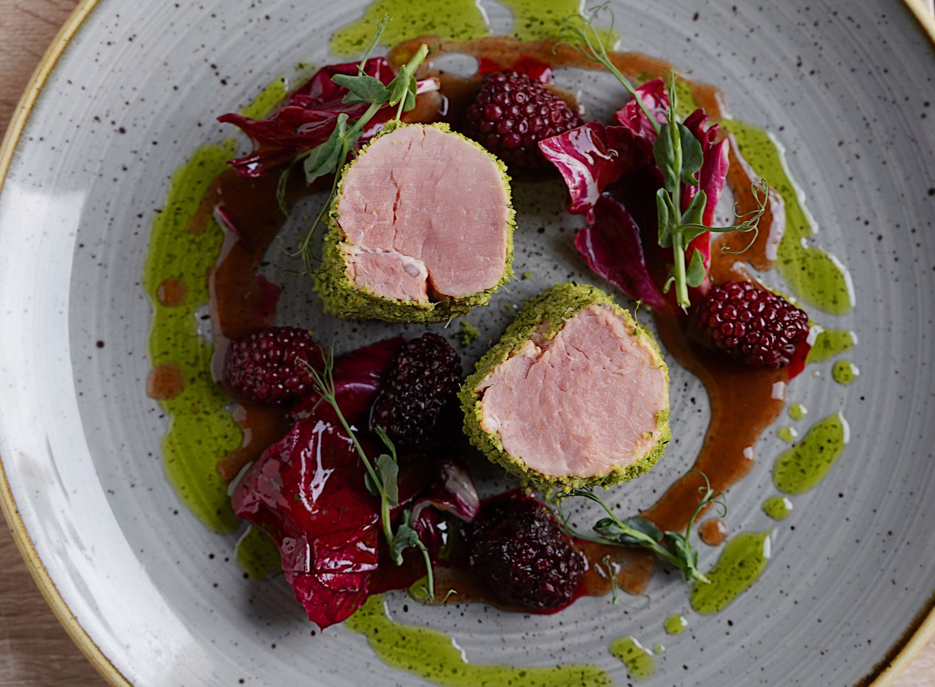 Pork tenderloin medallions with berries and beets on a gray plate