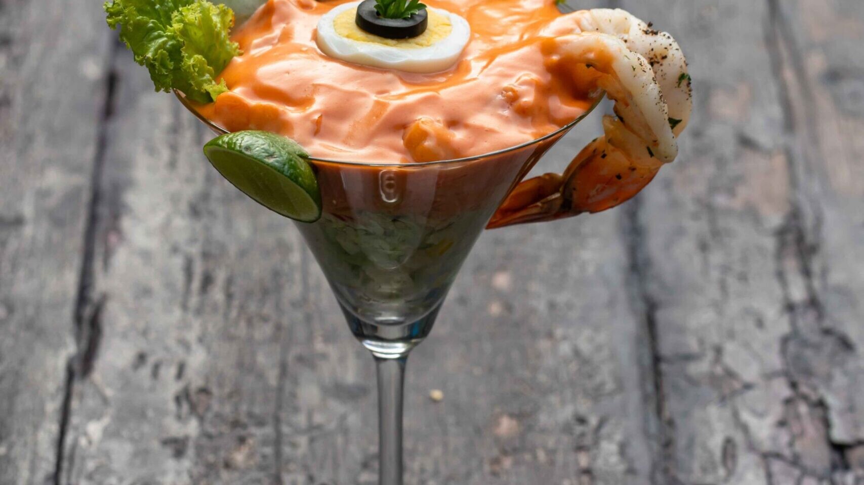 Shrimp cocktail in a martini glass on a rustic wooden table