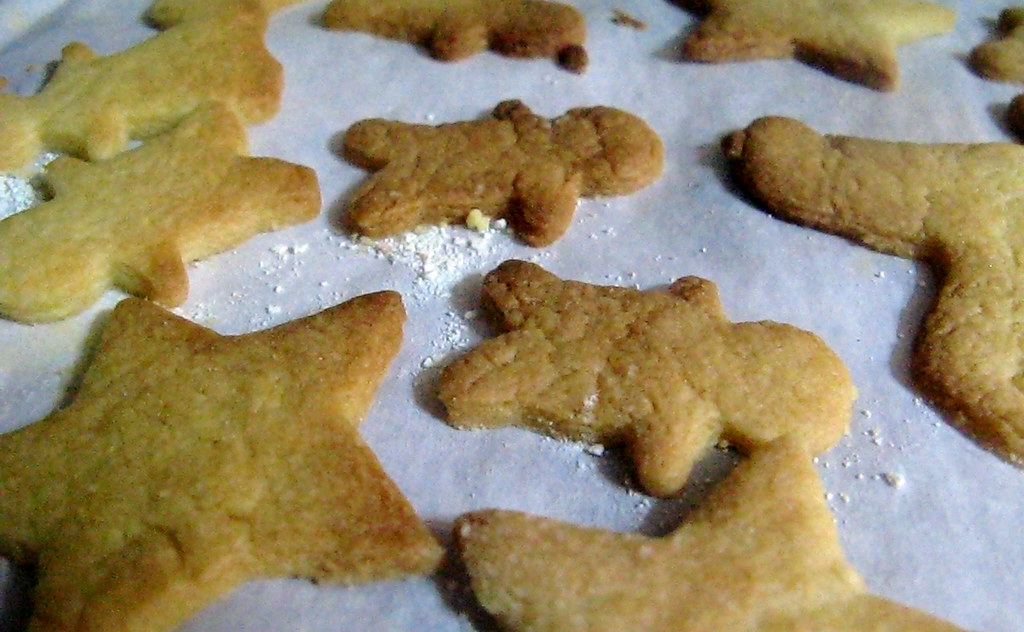 Golden brown star and gingerbread shaped cut-outs cooling on parchment