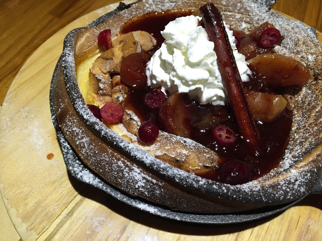Dutch baby pancake topped with cinnamon apples, berries and whipped cream