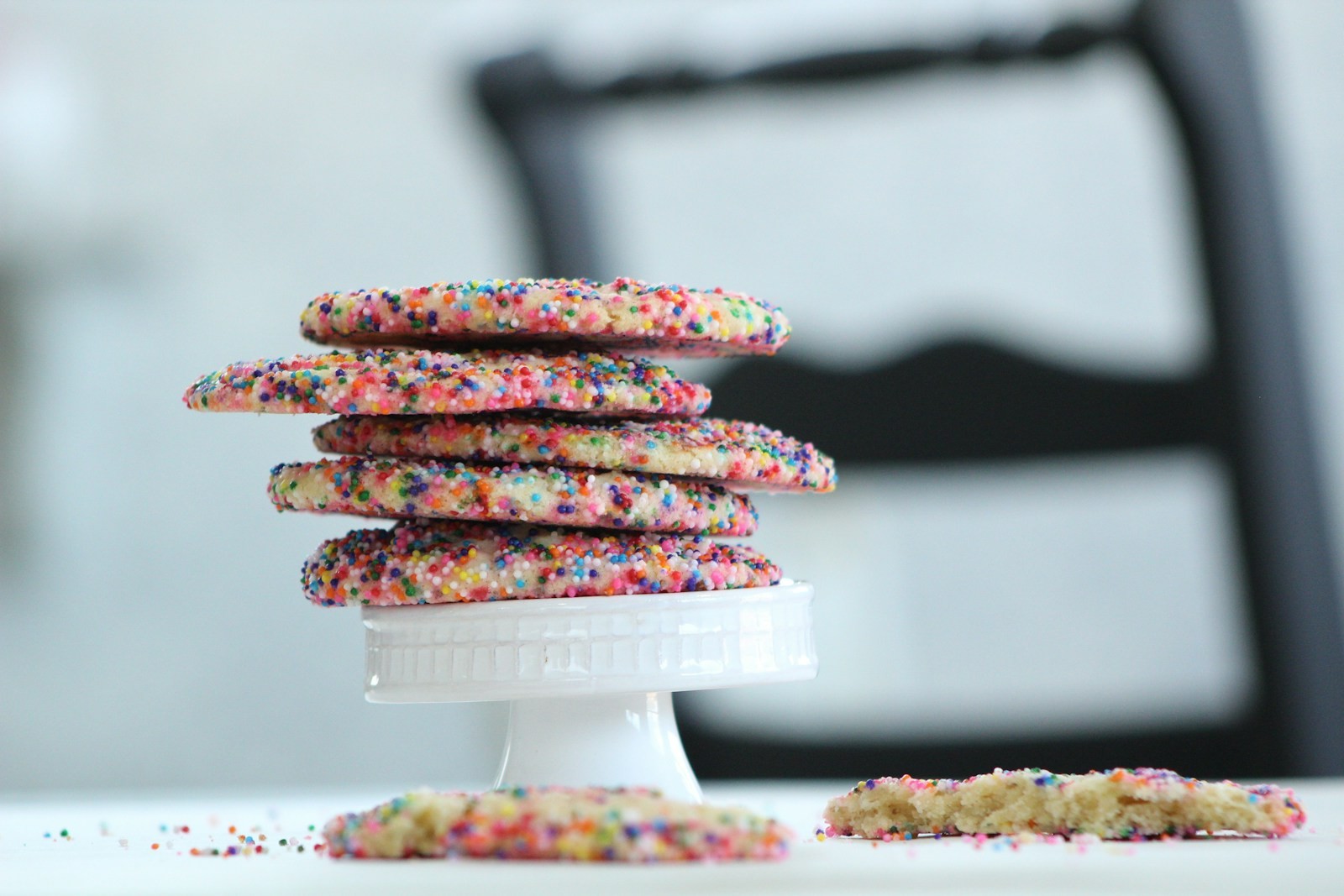 Stack of sprinkle-covered cake mix cookies on a white cake stand