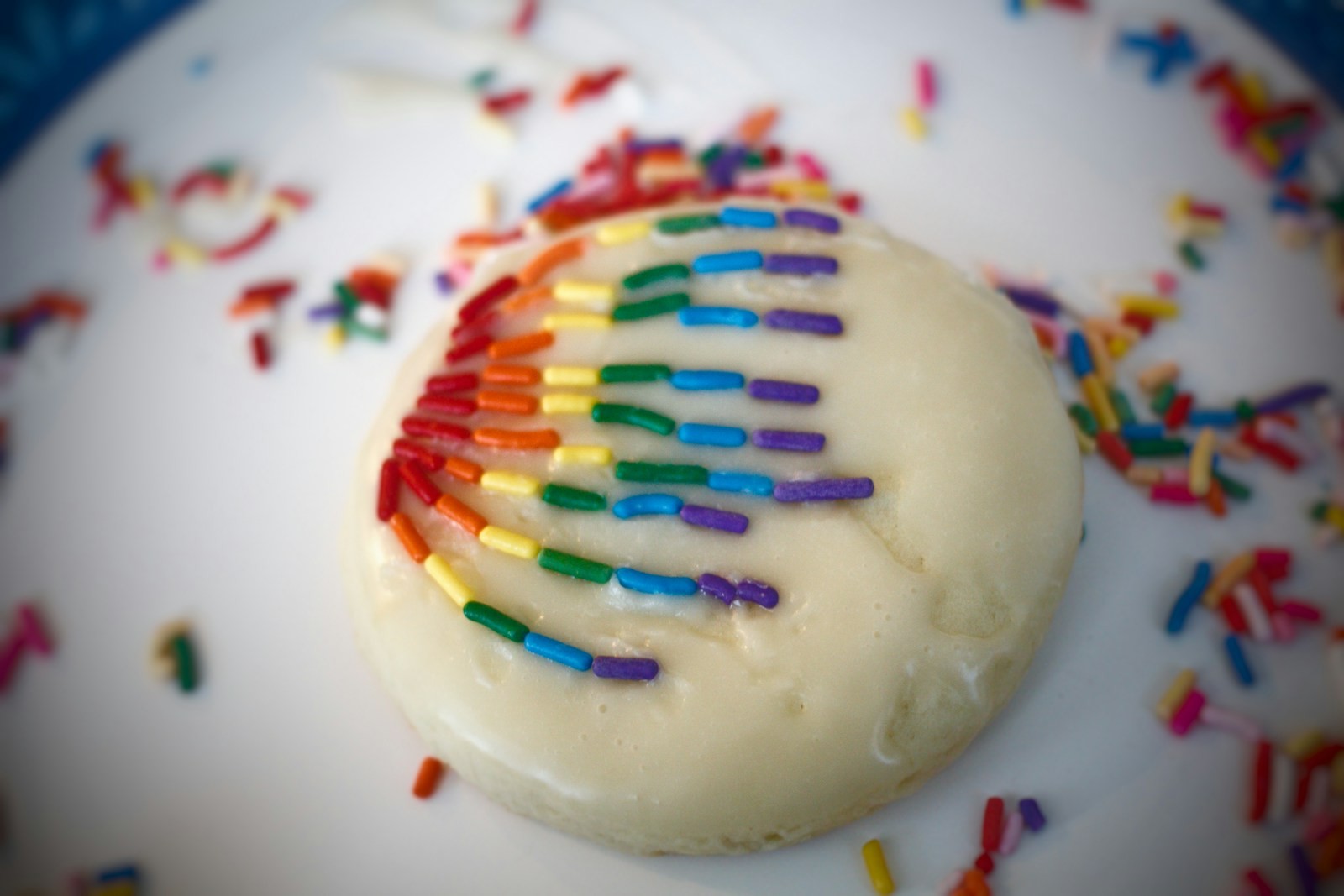 Glazed sugar cookie with a rainbow sprinkle arc