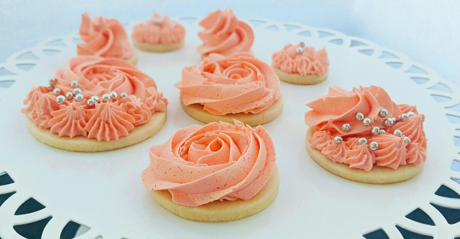 Peach frosting rosettes with silver dragees piped on round cut-outs