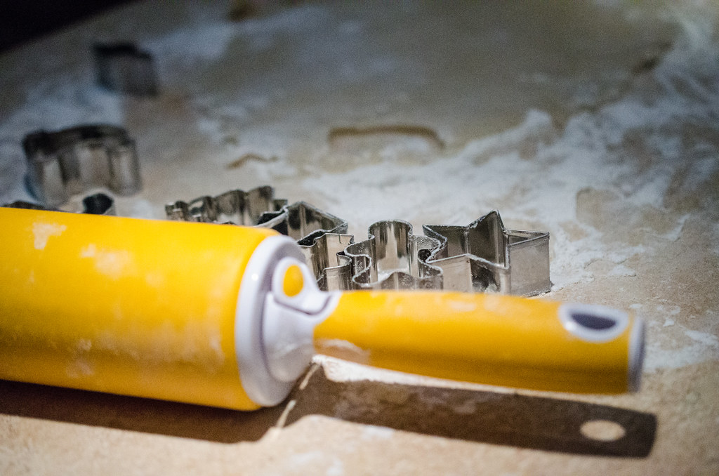 Rolling pin and metal cookie cutters resting on a floured board
