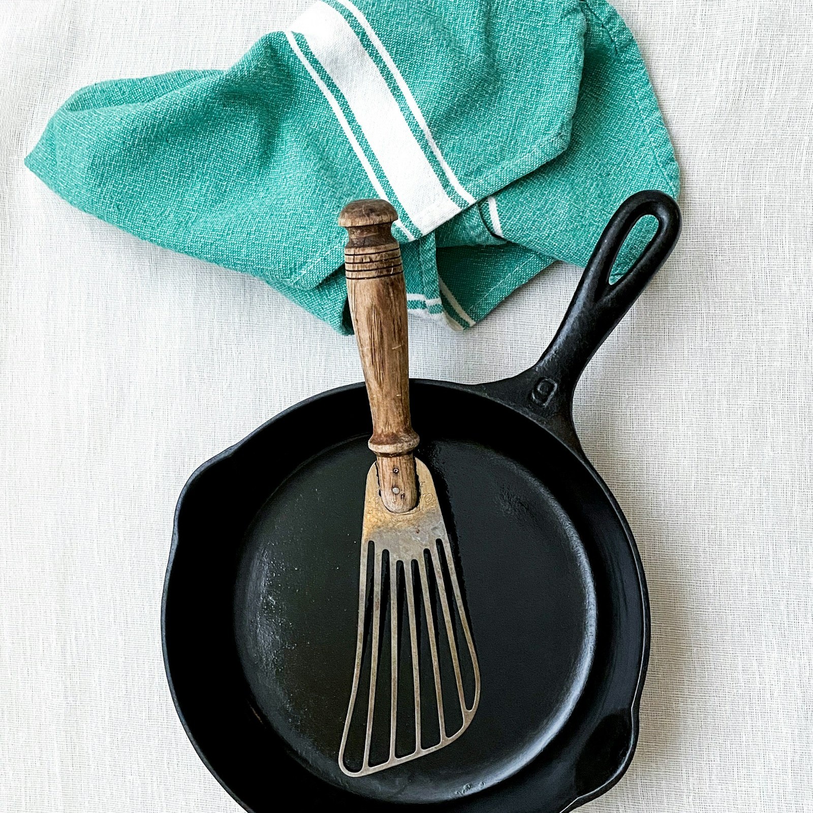 Clean, seasoned black cast iron skillet with a towel and spatula
