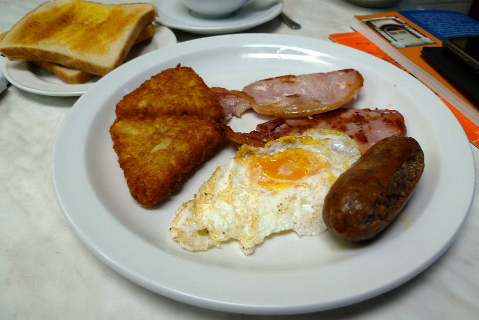 Breakfast plate of crispy fried potatoes with fried eggs and bacon
